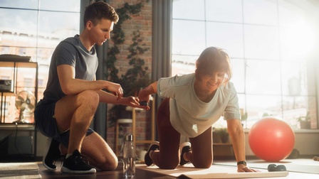 Eine Frau mit einem Personal Trainer beim ausführen von Sportübungen