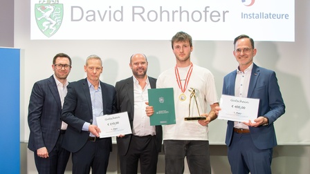 4 Männer und ein Jugendlicher stehen vor Präsentation und halten Urkunden hoch