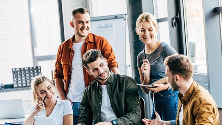 Gruppe von lachenden Personen in Besprechung