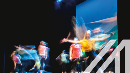 Gruppe von Tänzern in farbigen Kleidern tanzen auf der Bühne in Langzeitbelichtung