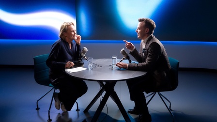 Zwei Personen sitzen am Tisch und reden ins Mikrofon