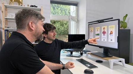 Zwei Menschen sitzen vor einem Computer-Bildschirm und sehen sich Bilder an