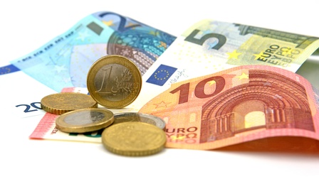 Ein 5-, 10- und 20-Euro-Geldschein auf weißem Hintergrund darauf sind Euro-Münzen platziert.
