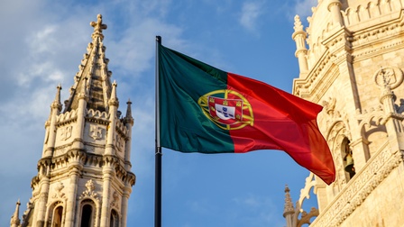 Die Flagge Portugals vor einer Kathedrale wehend.
