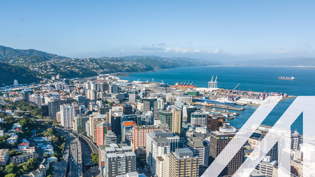 Blick auf Wellington, Neuseeland, und den Central Business District, mit vielen Wolkenkratzern, Hafen, Meer und Bergkette im Hintergrund<br />
