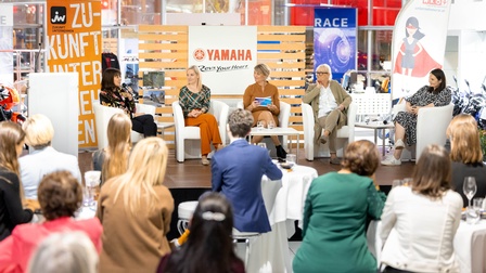 eine Gruppe Frauen auf einem Podium vor Publikum