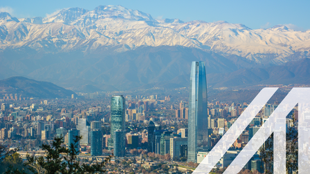 Städtebild Santiago de Chile: Panoramaansicht einer modernen Stadt mit Wolkenkratzern unter blauem Himmel, im Hintergrund sieht man die beschneiten Berge der Anden