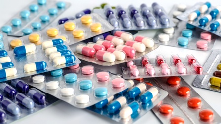 Auf weißem Untergrund liegen mehrere Verpackungen verschiedener Tabletten in unterschiedlichen Farben und Formen