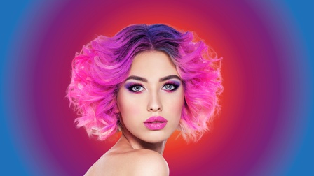 Frau stark pink und lila geschminktmit pinken Haaren und Locken.