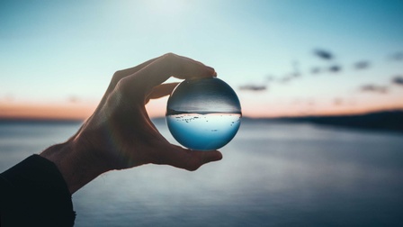 Eine Hand hält einen Linse gegen den Horizont