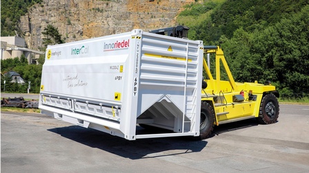 Nachhaltiger Container wird per gelbem Bagger transportiert