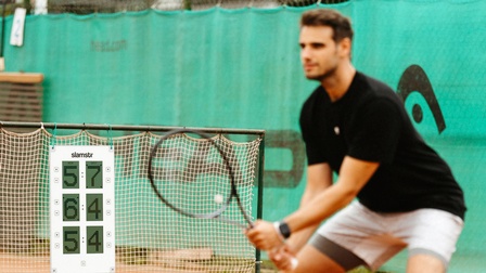Mann spielt Tennis, im Hintergrund die digitale Tafel