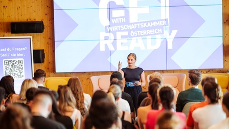 Moderatorin spricht zu sitzendem Publikum