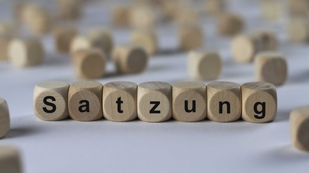 Sieben Holzwürfel nebeneinander mit Buchstaben, die das Wort Satzung ergeben