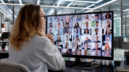 Eine Person sitzt an einem Schreibtisch vor einem Bildschirm 