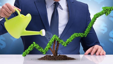 Businessman gießt eine Aufwärtschart, die aus Pflanzen besteht.