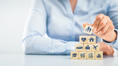 Detailansicht Hand stapelt verschiedene Würfel mit Symbolen