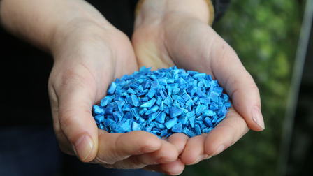 Hände halten blaues Plastikgranulat