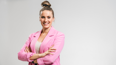 Porträt von einer jungen Frau mit verschränkten Armen mit rosafarbenem Blazer