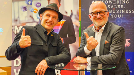 Zwei Referenten beim SIC FokusTalk stehen an einem Stehtisch, lächeln in die Kamera und zeigen mit erhobenem Daumen Zustimmung vor einem Banner zum Thema Digital Sales.