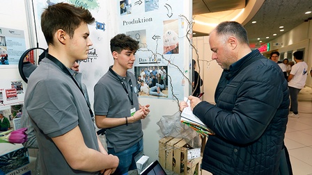 Drei Personen bei Messestand stehend