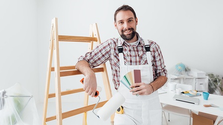 Maler stützt sich auf Leiter ab und hält eine Farbpalette in der Hand