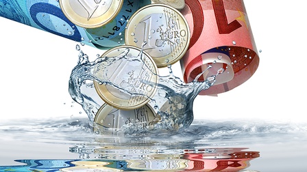Euromünzen und -scheine in Wasser eintauchend