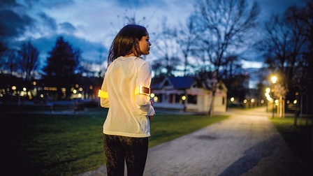 Eine Frau joggt im dunkeln und wird vom Flasher-Armband beleuchtet.