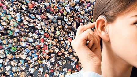 Ein Blick von oben auf eine Menschenmenge – davor sieht man eine Frau mit Hörgerät