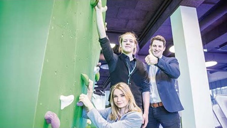 Lehrlinge und Ausbilder vor einer Kletterwand