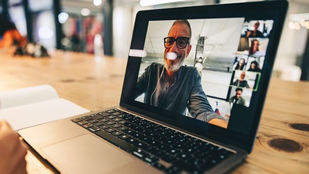 Aufgeklappter Laptopbildschirm mit mehreren Personen in einem Videocall