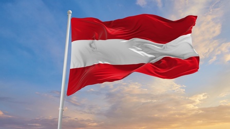 Flagge Österreichs weht im Wind, im Hintergrund wolkiger Himmel in Dämmerlicht