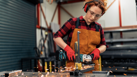 Ein rothaariges Mädchen bearbeitet Metall.