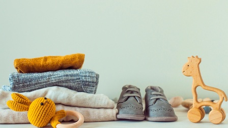 Holzspielzeug, Babyschuhe und Kleidung aus Bio-Baumwolle in einem Regal.