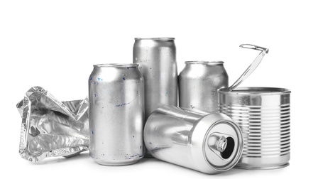 Vier stehende Aludosen, eine liegende Aludose und eine zerknüllte Aluverpackung auf weißem Unter- und Hintergrund