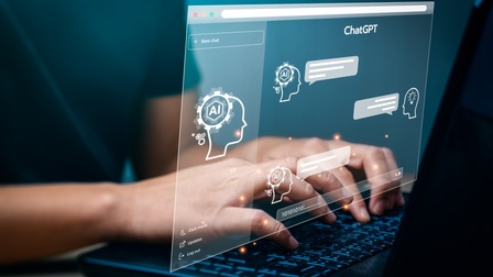 Die Hände einer Person liegen auf der Tastatur eines Laptops. Darüber ist grafisch eine Website gelegt. Innerhalb der Website steht ChatGPT sowie Ai. Außerdem sind darin Sprechblasen