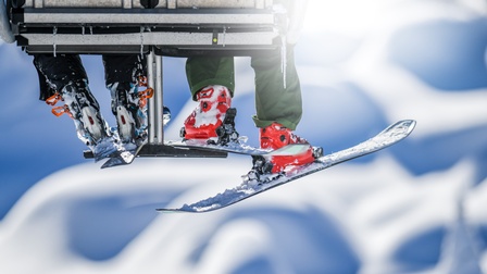 Nahaufnahme auf die Beine und Skier zweier Personen, die mit einem Skilift fahren.