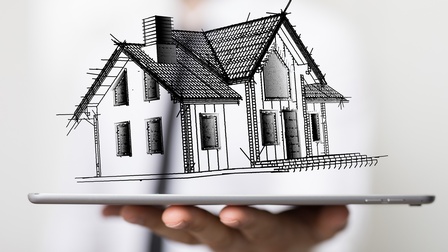 Gezeichnetes Einfamilienhaus schwebt über Tablet, das von einer Hand gehalten wird