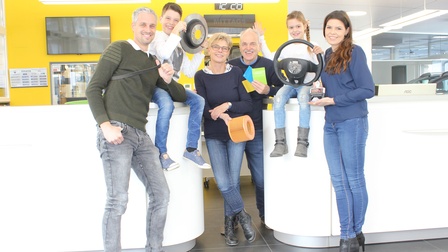 Die Familie gemeinsam - ein Kind hält ein Lenkrad, ein anderes ein anderes Autoteil