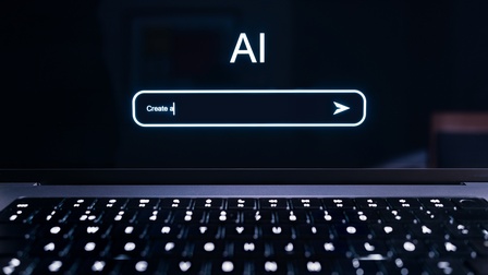 (KI-generierter Alttext) Nahaufnahme einer beleuchteten Tastatur vor einem Bildschirm mit dem Text 'AI' und einer Suchleiste mit dem Text 'Create a'.