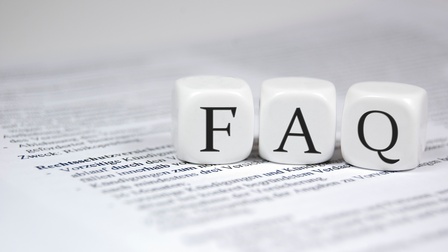 Drei weiße Würfel liegen nebeneinander auf einem bedruckten Papier. Auf dem linken Würfel ist ein f, dann folgt ein a und dann ein q