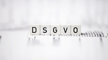 Weiße Würfel mit dem Aufdruck DSGVO, die auf einem textlichen Papier aufliegen und ringsum zeigt sich Unschärfe