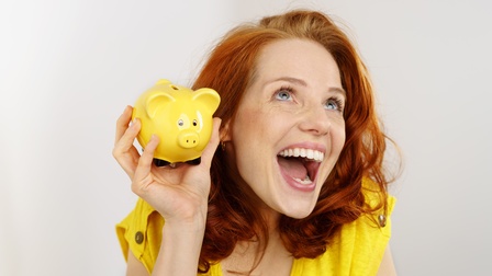 Glückliche Frau mit einem gelben Sparschwein 