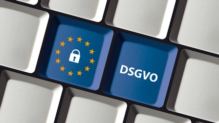 Nahaufnahme der Tasten einer Computertastatur. Zwei Tasten sind blau. Der Rest ist hellgrau. Auf der einen Taste ist ein Schloss, das von gelben Sternen umgeben ist. Auf der anderen Taste steht DSGVO