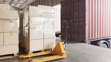 Mehrere Boxen auf Hubwagen, daneben steht ein LKW bereit für die Beladung