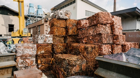 Gestapelte Kupfergegenstände vor Industrieanlage