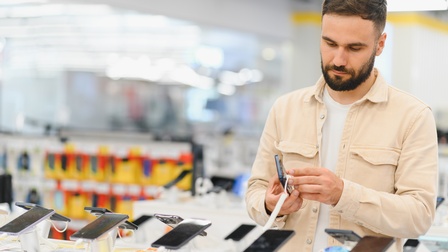 Eine Person steht in einem Elektrofachgeschäft und schau sich Smartphones an.