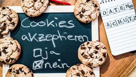 Auf einer Schiefertafel steht Cookies akzeptieren. Darunter kann man Ja oder Nein ankreuzen. Auf der Schiefertafel liegen Kekse. Daneben ist ein Notizblock, auf dem Datenschutz steht