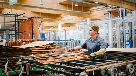 Person mit Brillen in Werkhalle stehend sortiert Solarpaneelleitungen