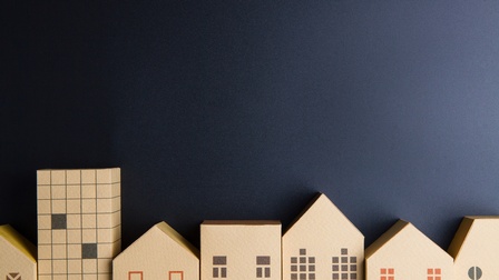 Modelle aus Pappe von verschiedenen Häusern vor einer schwarzen Papierwand